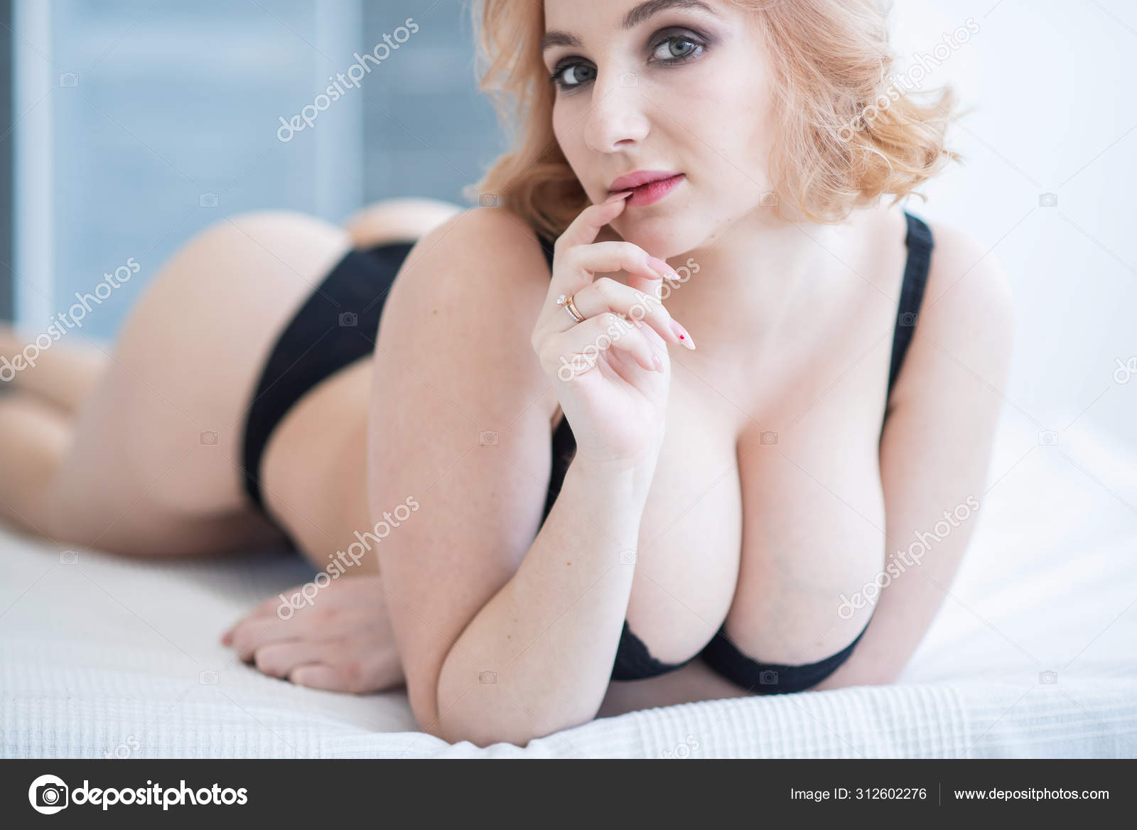 A European girl with a cute face and big Breasts in black underwear lies on her stomach picture