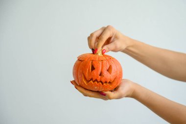 Cadılar Bayramı için balkabağı tutan kadın eller. Bir kadının yakın plan çekimi tüm azizlerin arifesinde beyaz bir arka planda kriko-fener kapağını açar. ön görünüm.