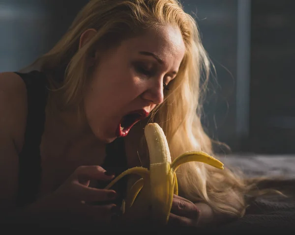 Una chica con el pelo largo y rubio se ve sexy en un plátano grande. Abre la boca y presenta sexo oral — Foto de Stock