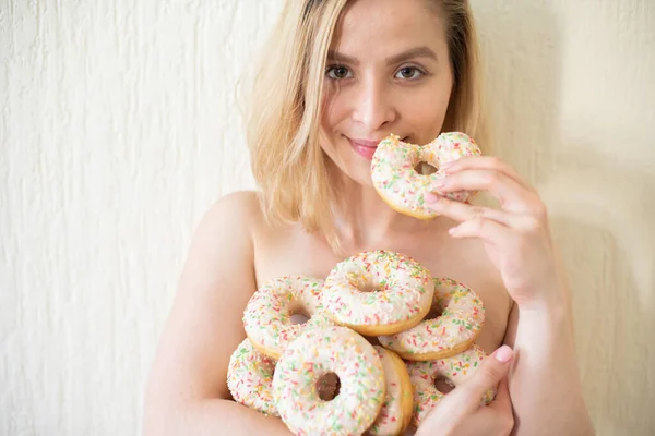 Оголена молода жінка їсть пончики. Портрет привабливої жінки з горою пончиків — стокове фото