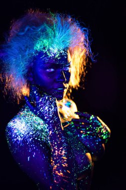 şeytan makyaj ve kontakt lensler. Ultraviyole vücut boyama kadın. Kız floresan tozuyla boyanmış. Uv ışıkta parlayan vücut sanatı. Gözlerindeki yıldızlar.