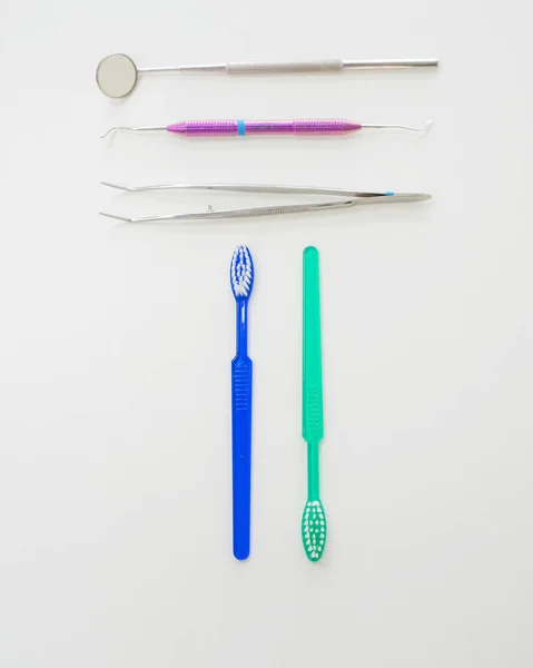 Mesa de dentistas con herramientas estériles en una vista superior de fondo blanco. Un espejo, unas pinzas, una sonda y un cepillo de dientes están en la mesa del doctor. Higiene bucal, prevención de caries, examen . — Foto de Stock