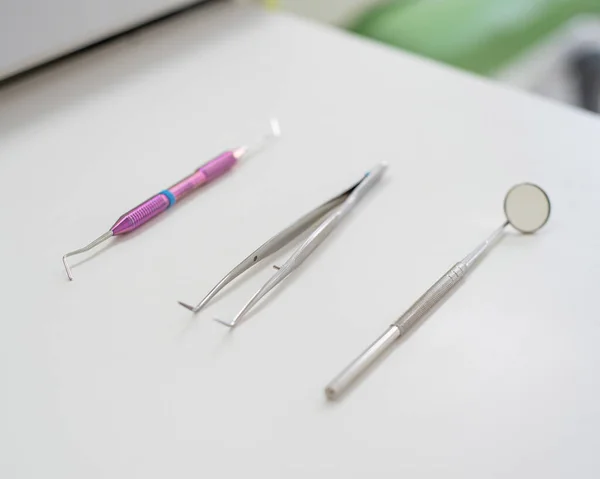 Instrumentos estéreis estão em uma mesa no consultório odontológico. Um espelho, pinças e uma sonda estão na mesa do médico. Higiene oral, prevenção da cárie, exame . — Fotografia de Stock