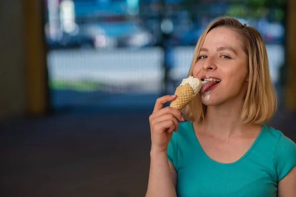 Портрет милої дівчини в зеленій сукні виходить на вулицю і їсть десерт. Красива блондинка насолоджується конусом з морозивом в прекрасний літній день. Життя - це задоволення — стокове фото