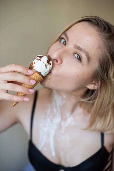 Sexy bionda lecca un cono cialda. Il gelato si sta sciogliendo, drenando eroticamente attraverso il corpo di una donna attraente. Bella ragazza spalmata di gelato. — Foto Stock