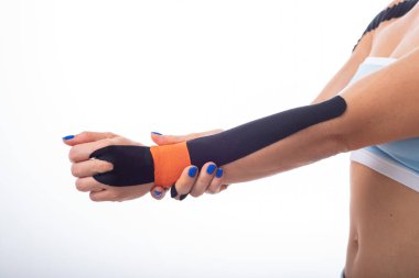 Bir kadın atlet bileğine kineziotape koyar. Kineziology, eklem ve tendon yaralanmaları için alternatif tedavi. Bir kadın kol eklemkronik iltihabı Fizyoterapi.