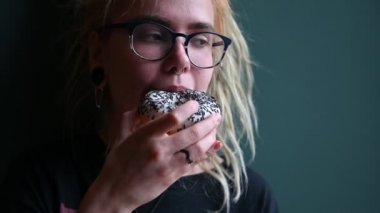 Kafasında rasta olan ve kafasında piercing olan alışılmadık bir kız bir kafede çörek yiyor. Gözlüklü genç bir kadın gri bir duvarda kahvaltı yapıyor. Yemek alışkanlıkları. İnsülin.