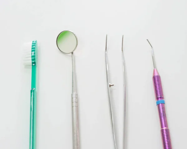 Dentists table with sterile tools on a white background top view. A mirror, tweezers, a probe and a toothbrush are on the doctor table. Oral hygiene, caries prevention, examination. — Stock Photo, Image