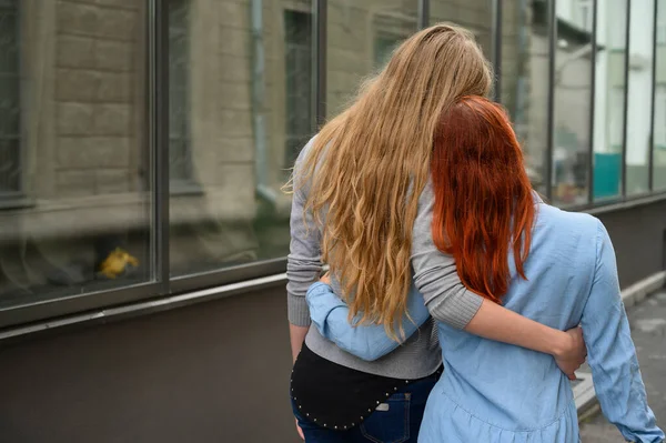 Relaties met hetzelfde geslacht. Een gelukkig lesbisch paar liep langs de straat en knuffelen zachtjes elkaar rond de taille. De rug van twee mooie vrouwen op een datum met een boeket van gedroogde bloemen. Lgbt. — Stockfoto