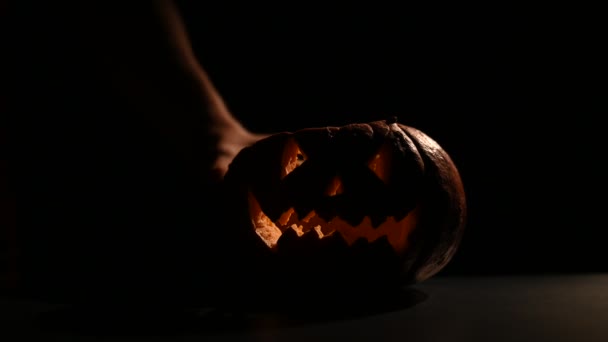 Halloween, orangefarbener Kürbis mit einem beängstigend leuchtenden Gesicht auf dunklem Hintergrund. stellt eine Kerze in die Buchse-o-Laterne. Nahaufnahme einer Taschenlampe am Vorabend aller Heiligen. — Stockvideo