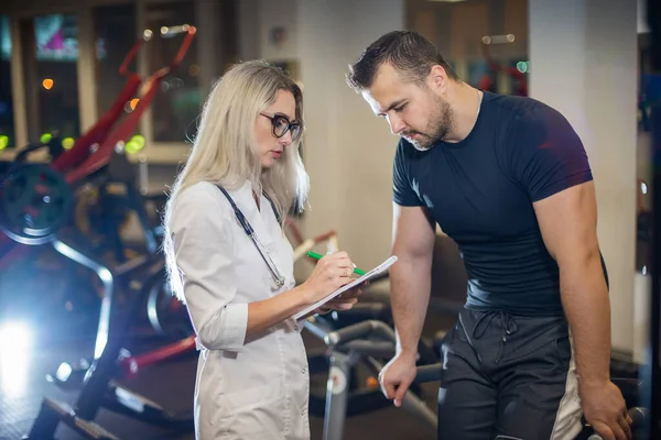 Medical examination. heart rate The doctor measures the pulse during a stress test. A female doctor measures a male athletes heart rate during classes on a treadmill.