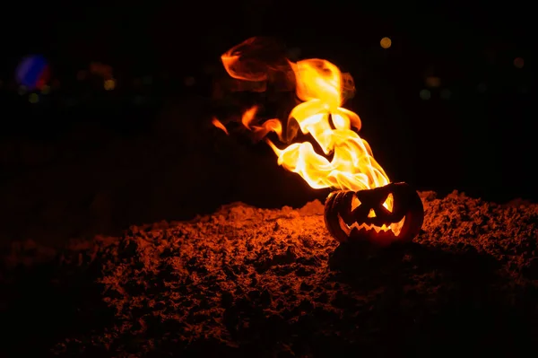 Tongen van vlam in een pompoen. Jack-o-lantern in brand op een zwarte achtergrond. Halloween symbool op de grond. Truc of behandelen. Close-up. — Stockfoto