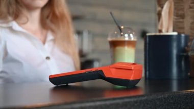 Kafenin kasasında çalışan bir bayan. Fotokopi kartı okuyucuları için parasız e-para cüzdanı olan kadın alıcının cep telefonu. Bir kadın yeşil soslu kahve ısmarlar..