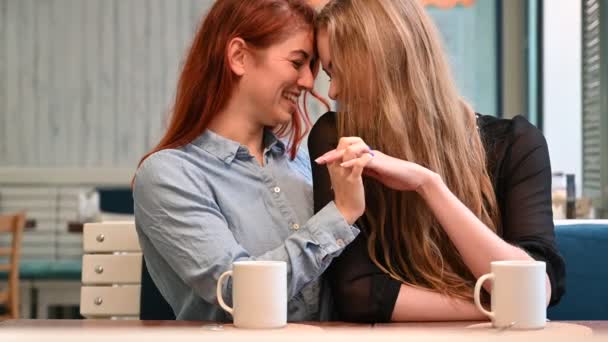 Relaciones del mismo sexo. Retrato de dos lesbianas sentadas en un café y tocándose suavemente. LGBT Joven amante de la pareja gay femenina. La proximidad de las mujeres . — Vídeos de Stock