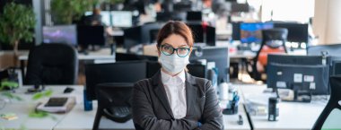 Ofisteki koruyucu maske ve eldivenli iş kadını. Gözlüklü ve takım elbiseli bir kadın yönetici koronavirüs salgınında çalışıyor. Personelin sağlığı ve güvenliği için. Maske kipi.