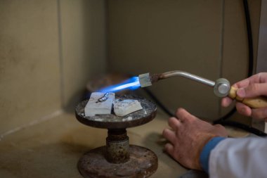 Bir diş teknisyeni kısmi takma diş yapar. Manüel gaz ocağı kullanılarak sahte çene ya da diş köprüsü üretimi. Yakın plan..