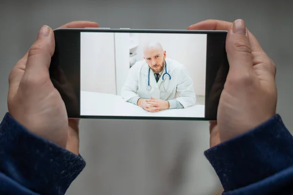 Medicina online. O paciente conversa com o médico através de um link de vídeo enquanto está em casa. Um homem dá uma consulta médica remota em um smartphone. Uma mulher está doente em casa e chama o terapeuta . — Fotografia de Stock