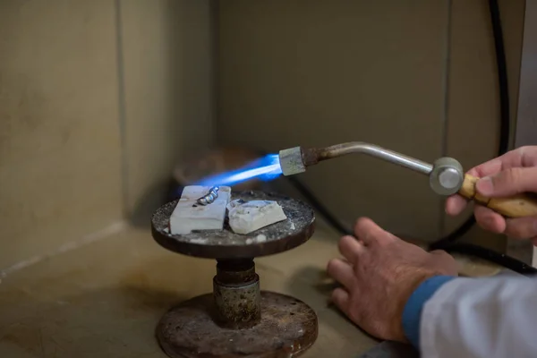 Un técnico dental hace dentaduras parciales. La producción de una mandíbula falsa o puentes dentales utilizando un quemador de gas manual. Primer plano . — Foto de Stock