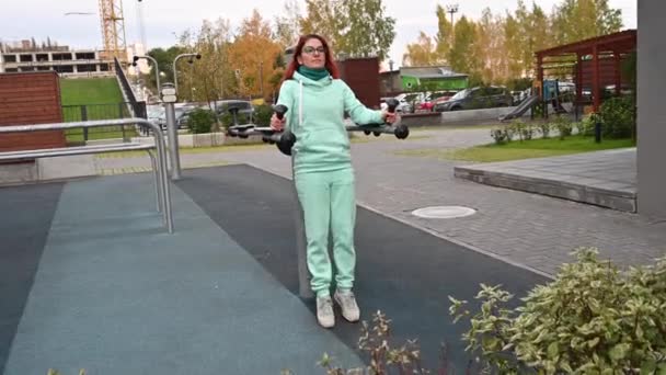 Una mujer hace deporte afuera. Simulador montado barra horizontal en un campo de deportes de calle. Una chica en un chándal caliente hace ejercicios en los músculos abdominales . — Vídeos de Stock