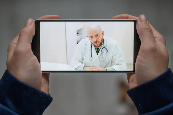 Medicina online. O paciente conversa com o médico através de um link de vídeo enquanto está em casa. Um homem dá uma consulta médica remota em um smartphone. Uma mulher está doente em casa e chama o terapeuta . — Fotografia de Stock