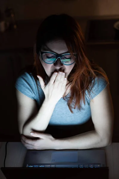 Femme fatiguée travaillant sur un ordinateur portable à distance de la maison. Une fille épuisée bâille en utilisant un ordinateur pour étudier. L'étudiant se prépare pour l'examen. Portrait indépendant la nuit . — Photo