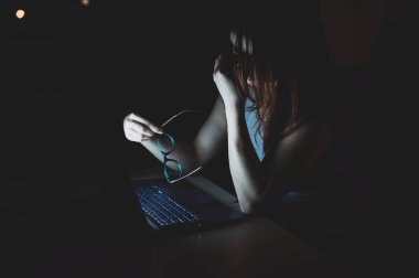 Dizüstü bilgisayarla uğraşan yorgun kızıl saçlı kadın. Umutsuzluk içinde bilgisayarın başındaki kız burun köprüsünde el ele tutuşuyor. İşteki başarısızlık. Son teslim tarihi ve fazla mesai.