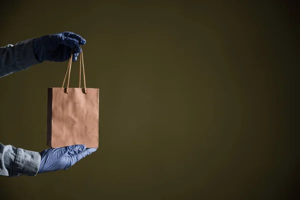 Entrega domiciliar expressa na epidemia de coronavírus. Correio em luvas com um saco de papel. Embalagem feita de material reciclado ecológico. Comprar produtos on-line em quarentena . — Fotografia de Stock