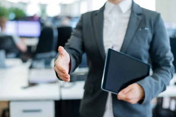 La trabajadora de oficina extiende su mano para saludarla. La dama de negocios sin rostro sostiene una tableta digital y un apretón de manos en un acuerdo para una transacción exitosa . — Foto de Stock