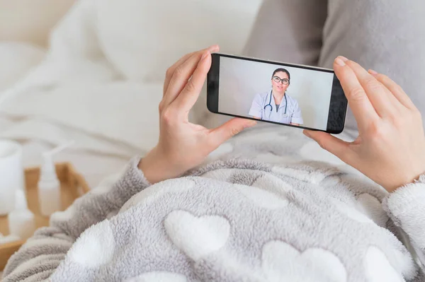 一名妇女在家中被隔离，正在与病毒学家举行视频会议。病人躺在床上，手里拿着电话。医生的电话. — 图库照片