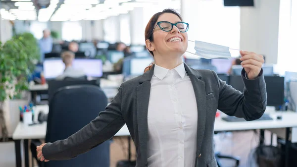 La mujer de negocios se quita la máscara en la oficina al final de la cuarentena. El coronavirus ha terminado. La chica respira libremente y cierra los ojos en el placer. Victoria sobre la pandemia . —  Fotos de Stock