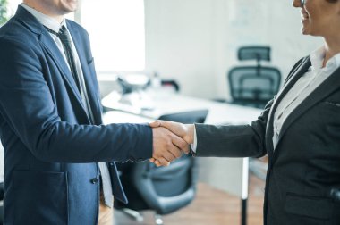 İş adamı ve kadın tokalaşması başarılı bir alışverişin sonunda. Karşılama sırasında takım elbiseli ofis çalışanları. Başarılı iş görüşmesi.