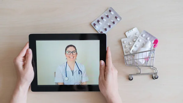 Mosolygó női orvos a képernyőn egy digitális tabletta. A háziorvos online kinevezése. Mini gyógyszeres kocsi. Távoli konzultáció. — Stock Fotó