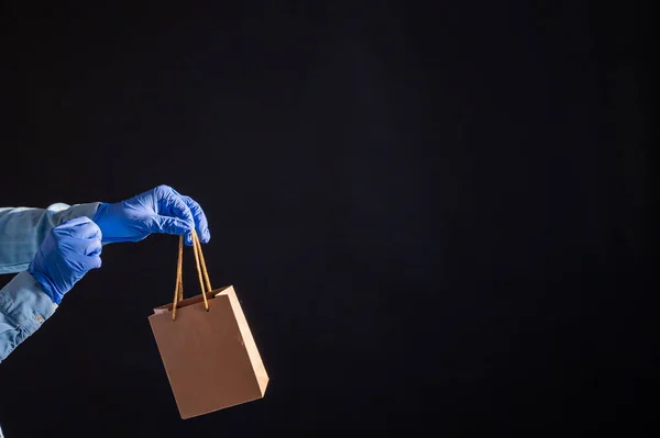 Express-Lieferung nach Hause in der Epidemie des Coronavirus. Kurier in Handschuhen mit Papiertüte. Verpackungen aus umweltfreundlichem Recyclingmaterial. Online-Kauf von Produkten in Quarantäne. — Stockfoto