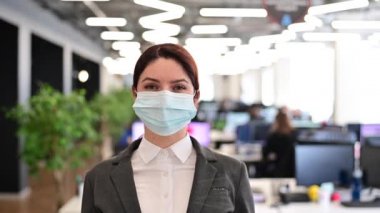 Takım elbiseli neşeli kadın ofiste maskesini çıkarıyor. İş kadını karantina sonunu kutluyor. Virüse karşı zafer. Şenlik havası. Maskesiz nefes verme.