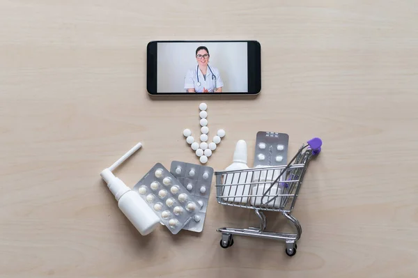 Friendly female doctor on a smartphone screen prescribes treatment. Online medicine. Mini trolley with pills. Remote consultation. Mobile application pharmacy.