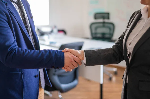 Handshake of unrecognizable business persons as a gesture of a successful deal. Hands of office workers in suits during a greeting. Partnership agreement. Faceless managers.