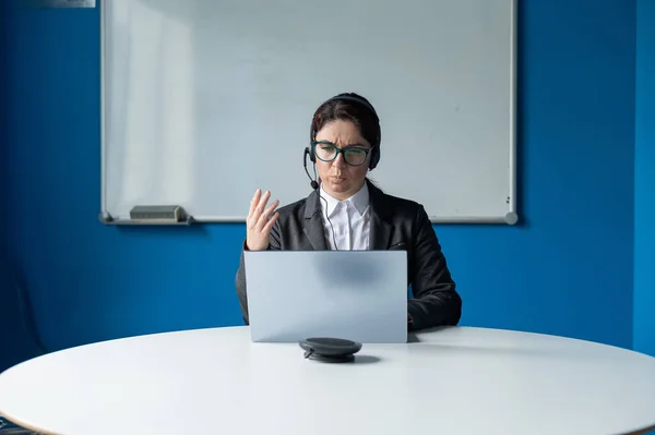 Una mujer enojada en un auricular está teniendo una conversación en línea en una computadora portátil en una sala de conferencias. Jefa regañando subordinadas para una videollamada. Negociaciones comerciales remotas infructuosas . — Foto de Stock