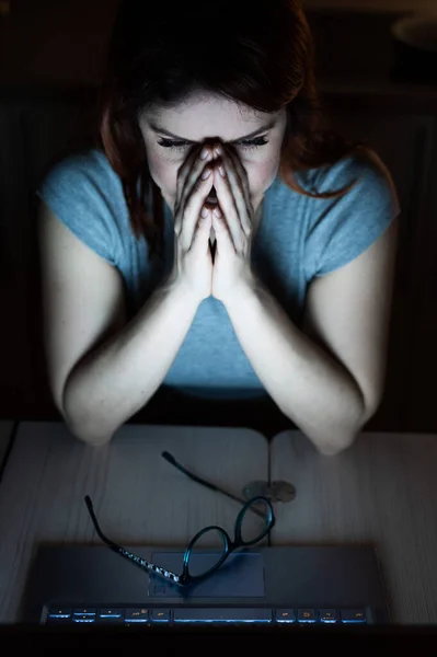 Trött, utmattad kvinna i frustration arbetar övertid på en bärbar dator. En kvinnlig frilansare i desperation håller händerna i ansiktet. Nattarbete hemifrån. Tidsfrist — Stockfoto