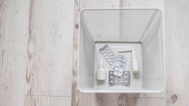 Beyaz ağlı metal çöp sepetinde ilaç. Üst Manzara. Haplar çöpe atıldı. İçinde ilaçların olduğu bir kağıt sepet..