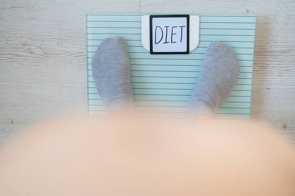 Top view of female legs in socks standing on the floor scales. The inscription on the diet display. A woman with a bare stomach and obesity should lose weight. — Stock Photo, Image