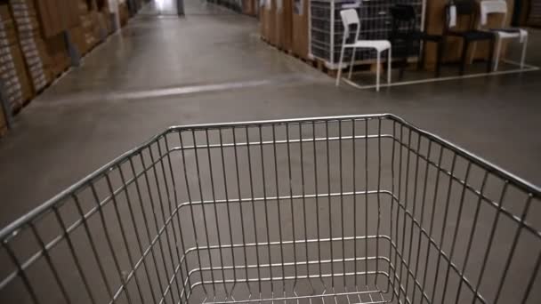 Carrello della spesa vuoto in un magazzino di mobili. Supermercato carrello corridoio con scatola scaffale astratto sfocatura sfondo sfocato — Video Stock