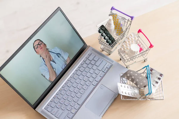 Online medicine and pharmacy concept. A female doctor conducts an online consultation and recommends medications. Mini trolley with tablets at the laptop.