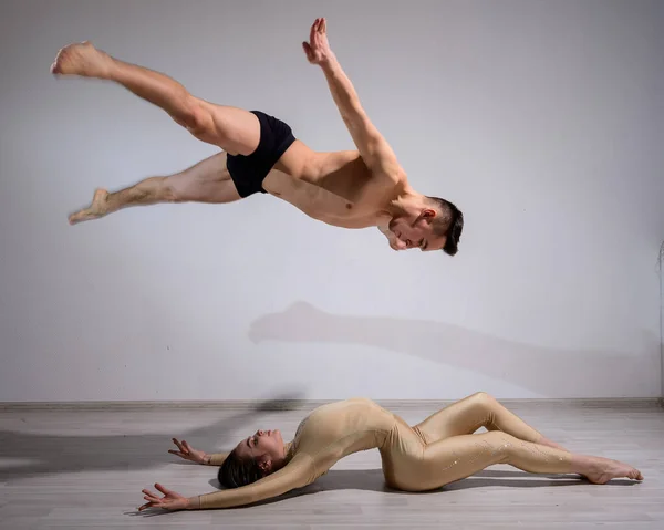 Couple acrobatique effectuer numéro sur un fond blanc. Un duo de gymnastes répétant une performance avec soutien. Un homme et une femme très flexible dansent. — Photo