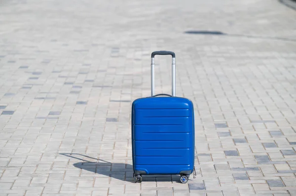 人行道上轮子上的蓝色行李箱.行李在城市的街道上，准备好了旅行。大包的移动。没有人. — 图库照片