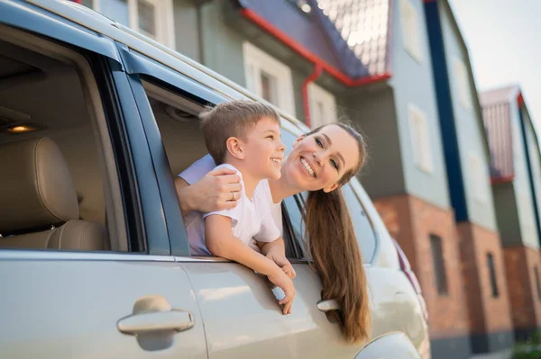 Mutlu kadın ve çocuk pencereden dışarı bakar. Annesiyle birlikte neşeli çocuk arabanın arka koltuğunda oturuyor ve yolculuk için hazır. Yaz tatili kavramı. Aile gezisi. — Stok fotoğraf