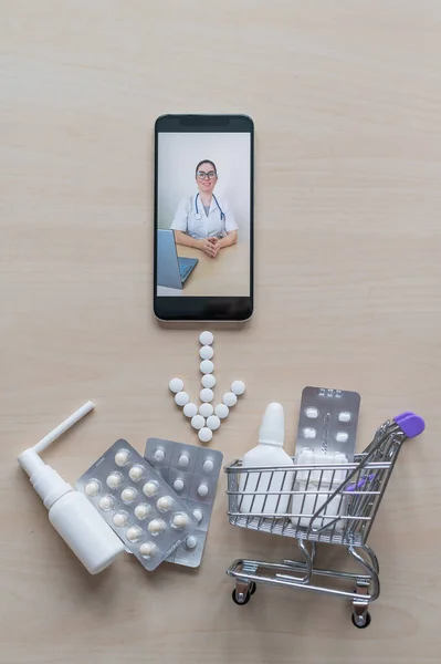 Friendly female doctor on a smartphone screen prescribes treatment. Online medicine. Mini trolley with pills. Remote consultation. Mobile application pharmacy.