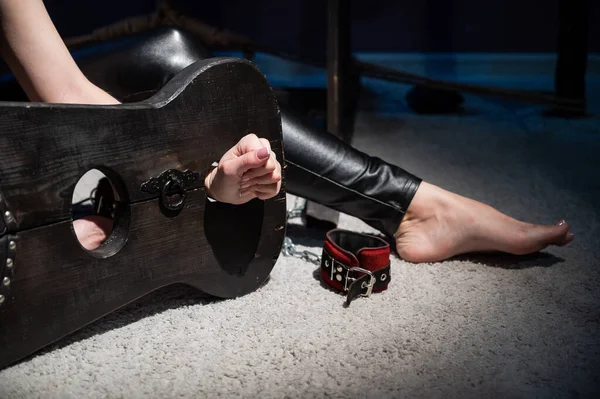 Female hands in wooden shackles during role-playing games. Shameful pillar and leather cuffs for sex. BDSM Domination and punishment.