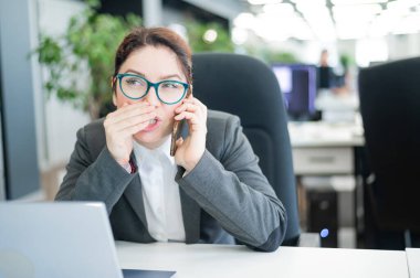 Ofisinde bir kadın oturuyor ve telefonda dedikodularını yapıyor. Şirket ahlakı. Takım elbiseli kadın çalışan, iş yerindeki akıllı telefondan sırlarını anlatır..