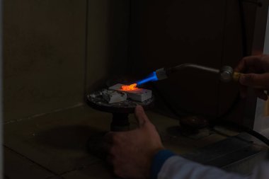 Bir diş teknisyeni kısmi takma diş yapar. Manüel gaz ocağı kullanılarak sahte çene ya da diş köprüsü üretimi. Yakın plan..