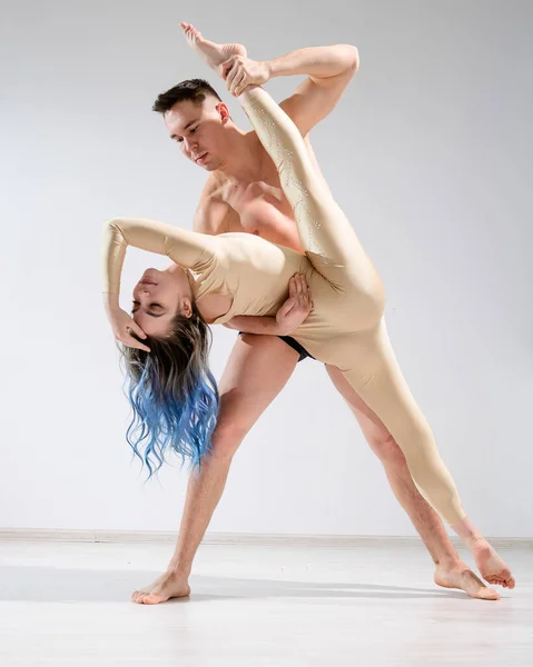 Una coppia di ballerini in azione. Un giovane duetto di artisti circensi si esibisce con spago in studio. Uomo in mutande tenendo donna in tuta per la ginnastica nelle spaccature. — Foto Stock